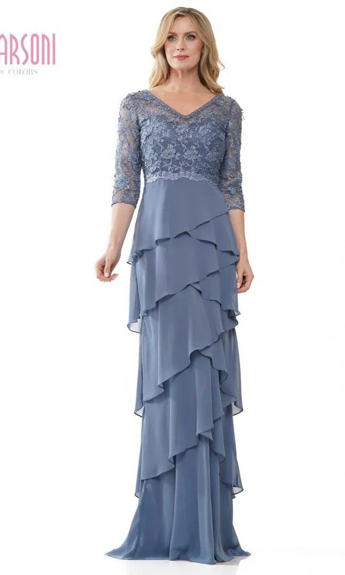 A woman stands against a white background wearing the Marsoni MV1244 long formal dress in slate blue, featuring a lace embroidered bodice, three-quarter sleeves, and a chiffon tiered column skirt.